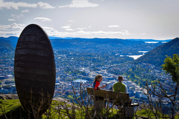 A couple sitting on a bench admiring the view over Bergen from Mount Floyen