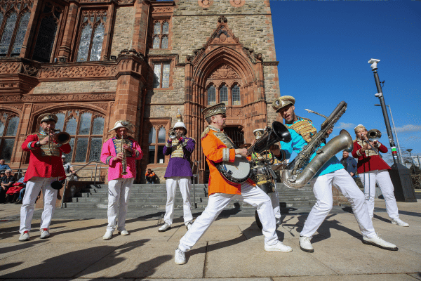 Band playing musical instruments on a Derry street