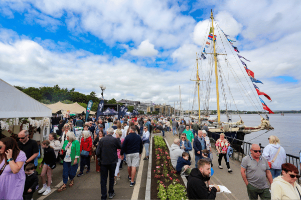 People on the waterfront in Derry with stalls to their left and ships to their right