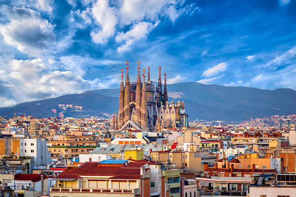 Sagrada Familia sticking out from surrounding buildings with mountains in background