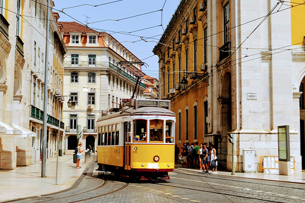 Yellow tram going down a street in Lisbon with buildings immediately either side