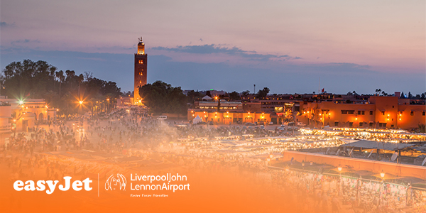 Main square in Marrakesh at night with market stalls in the foreground and the tower of Koutoubia Mosque in the background
