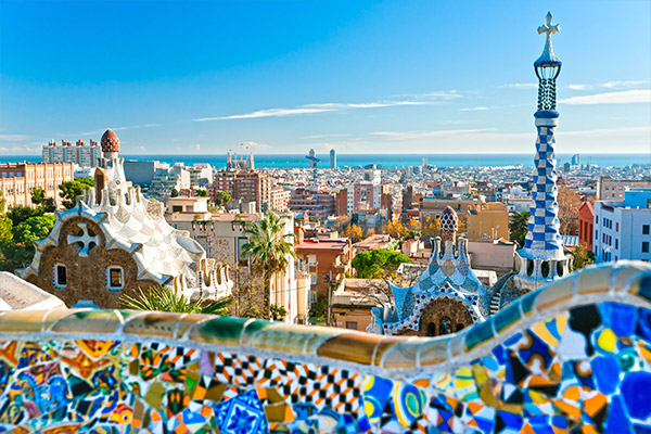 View of Barcelona skyline in background and a tiled bench of Park Guell in the foreground