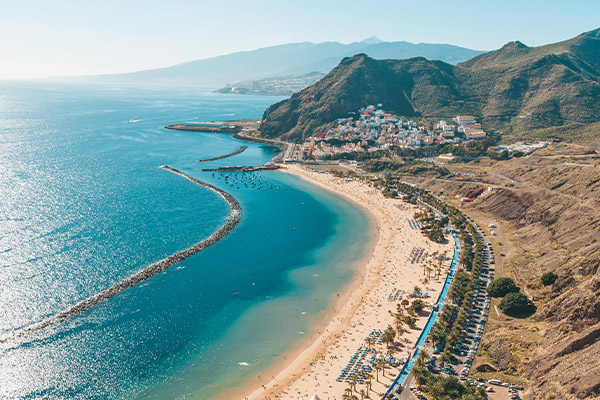 Aerial shot of long beach with rocky hill in the background
