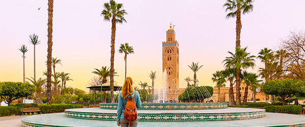 Lady stood next to fountain looking at the minaret of Koutoubia Mosque