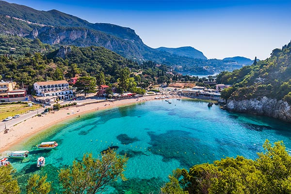 Shallow blue waters and a beach surrounded by mountains in Corfu