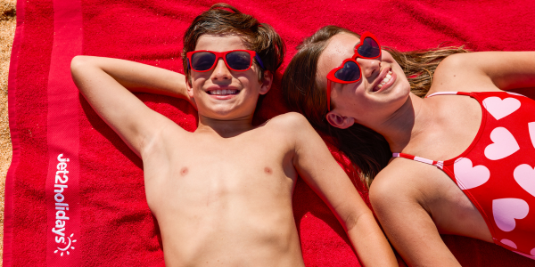 Two kids lying on a Jet2holidays towel