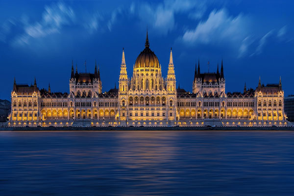 Illuminated Hungarian Parliament Building on the bank of the Danube river at night.