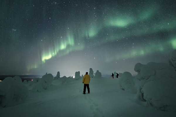 A man looking up at the Northern Lights in Kittilä.