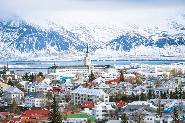 Skyline of Reykjavik with snow-covered mountains in the background.