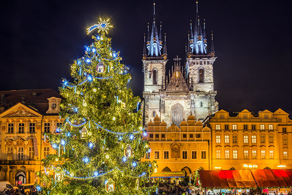 Christmas tree in the middle of a square in Prague, overlooked by a church