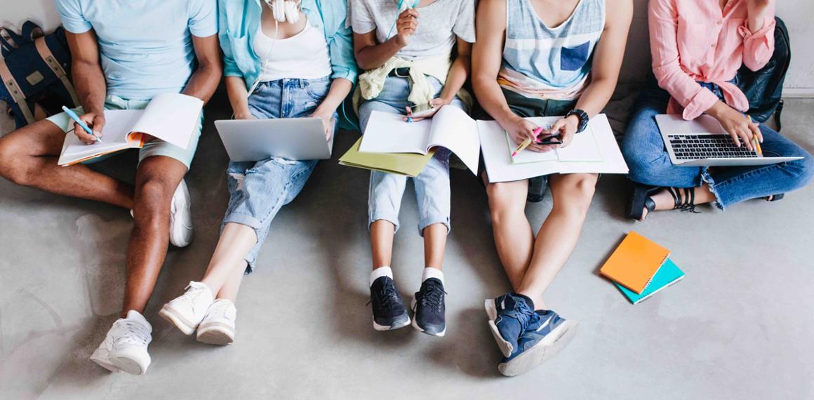 Groep studenten met schriften en laptops