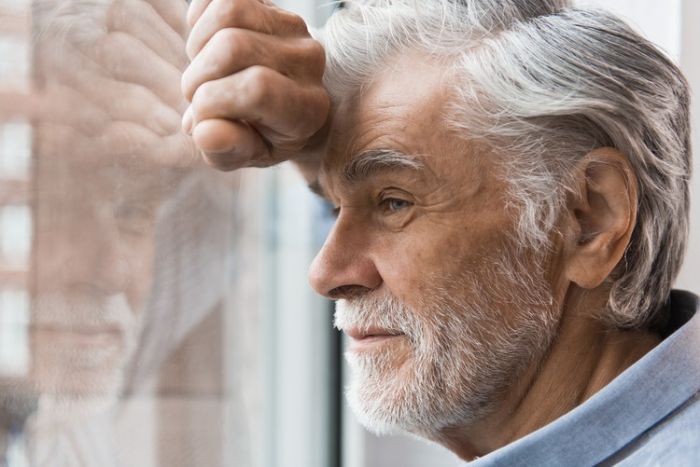 man leunend tegen raam naar buiten kijken