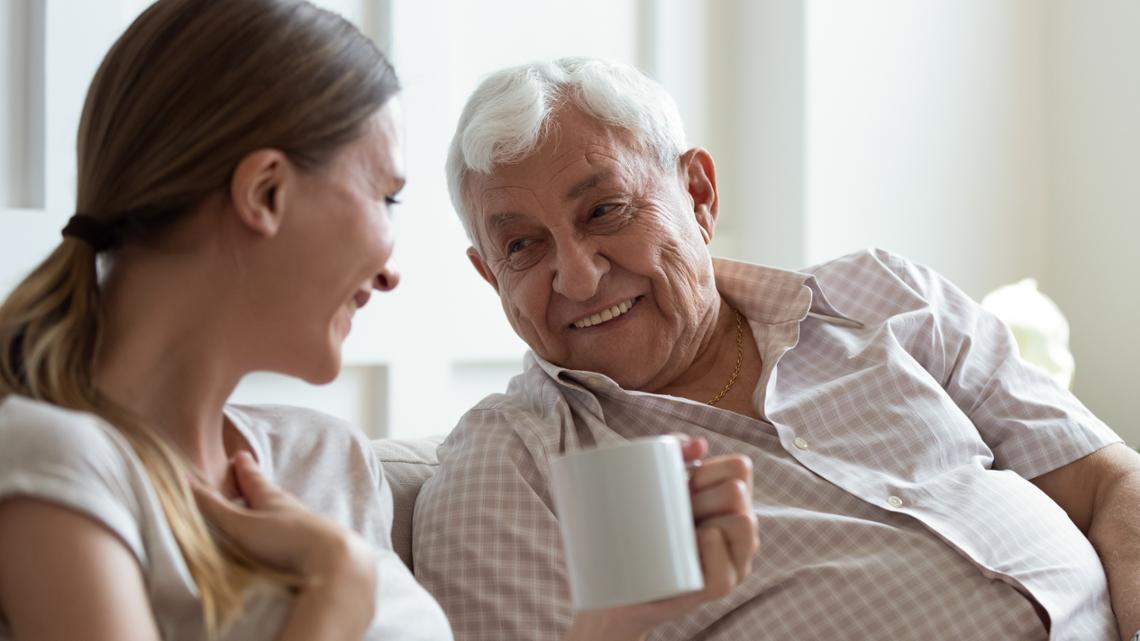 Een vrouw en een oudere man in gesprek, ze lachen naar elkaar