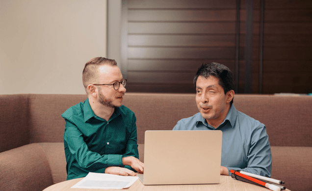 twee collegas met zichtbare handicap in gesprek met laptop