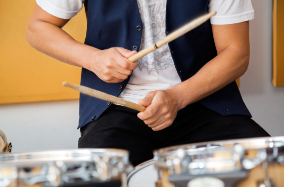 Persoon is aan het drummen met drumsticks