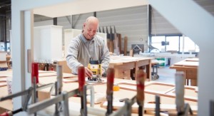 Een man in werkkleding is aan het werk in een houtwerkplaats.