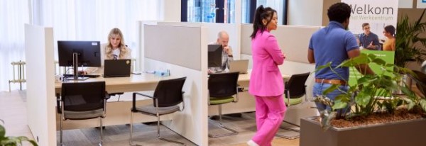 Een vrouw zit achter een bureau in een kantoortuin