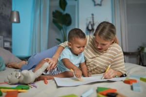 en vrouw en een baby zitten samen op bed een papiervel in te kleuren