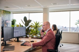 Een man zit achter een bureau te bellen