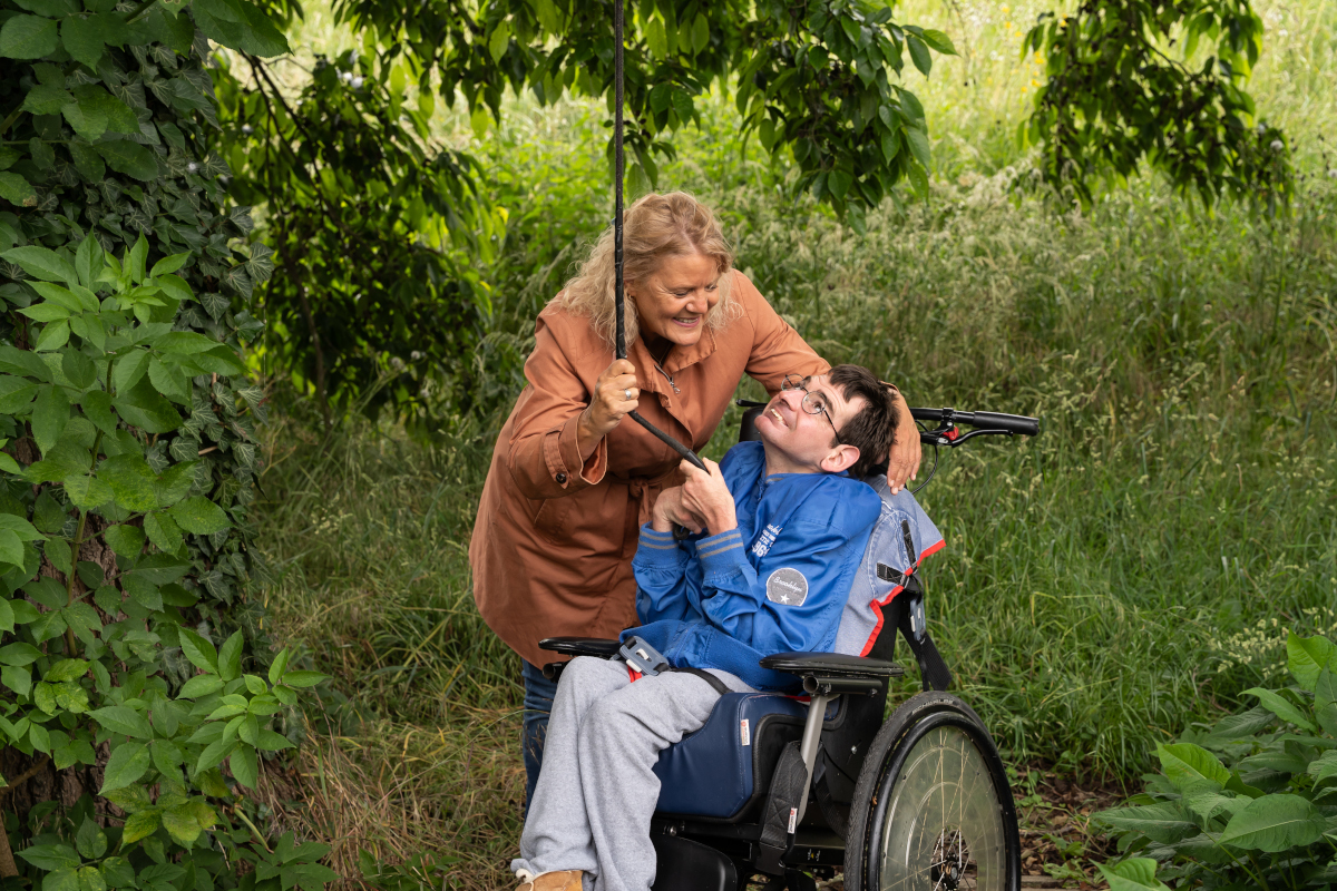 Begeleider trekt samen met haar cliënt aan een touw die aan een boom is vastgemaakt