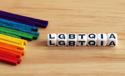 Gekleurde stokjes in de kleuren van de regenboogvlag. Daarnaast liggen kraaltjes met de letters lgbtqia erop.