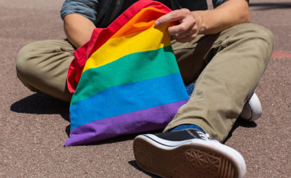 Iemand zit op de grond en haalt iets uit een regenboogtasje.