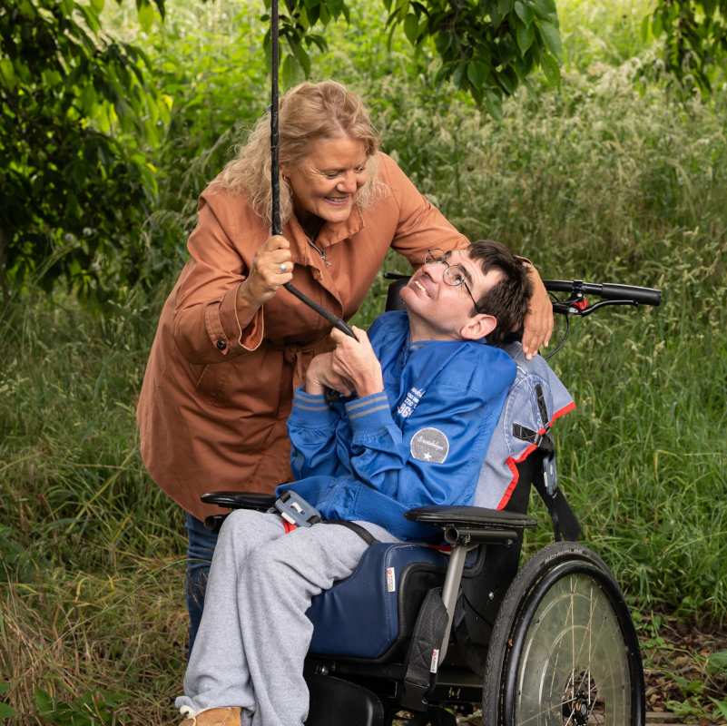 Begeleider en cli&euml;nt uit de complexe gehandicaptenzorg trekken samen aan een touw die aan een boom hangt