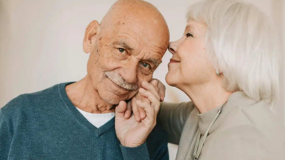 Oudere vrouw die oudere man kust