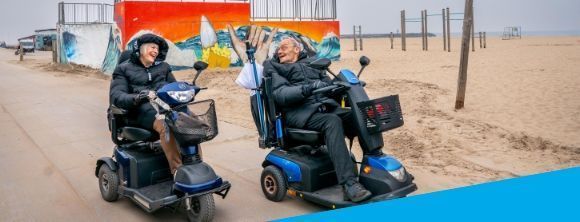 Ouderen in scootmobiel op het strand