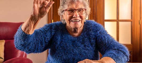 Oudere vrouw die gewichten optilt en daarbij wordt geholpen door een verzorgende