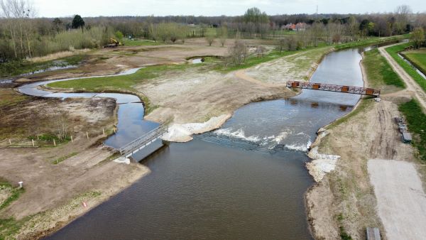 Een dronefoto van de Essche Stroom met nieuwe stuw, de wandelbrug en de nieuwe loopbrug over de instroom van de vispassage 