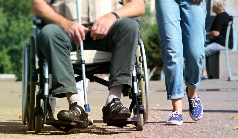 Persoon in een rolstoel met een wandelstok naast een wandelend persoon