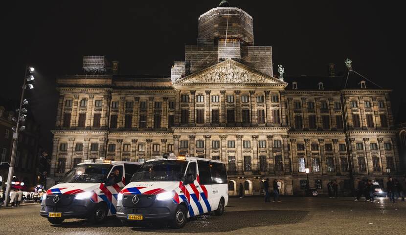 Paleis op de Dam in de avond met twee politiebussen op het plein