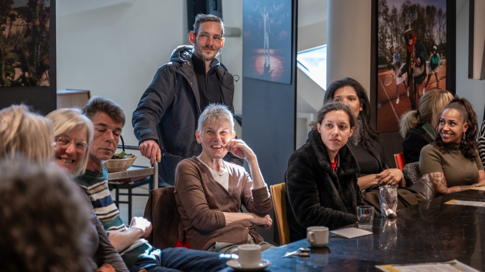 Groep mensen in gesprek met elkaar bij een koffietafel