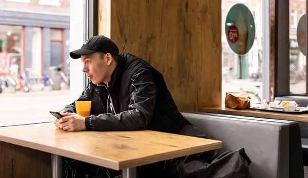 Dak- en thuisloos persoon zittend en naar buiten starend in een horecagelegenheid