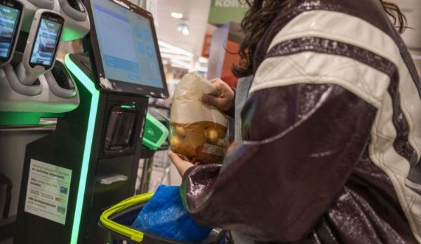 Vrouw rekent een zak aardappelen af bij een zelfscankassa van een supermarkt