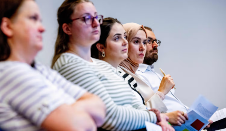 Vijf zittende bezoekers tijdens een bijeenkomst van Platform Gemeenten en Mensenrechten