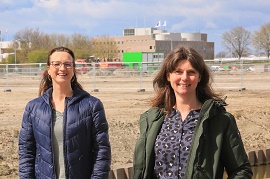 Foto van 2 vrouwen. Op de achtergrond een nieuwbouwlocatie en kantoren.