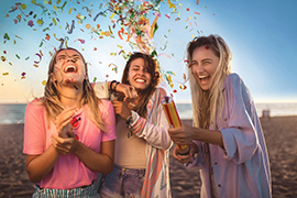 3 lachende, jonge vrouwen op een strand met confetti
