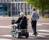 vrouw in rolstoel met hulp naast haar