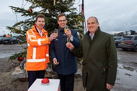 3 mannen voor een kerstboom. Ze prossten met een glas champagne.