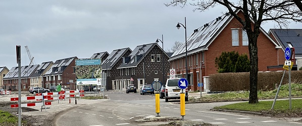 Een straat met links een stukje fietspad en rechts woningen.
