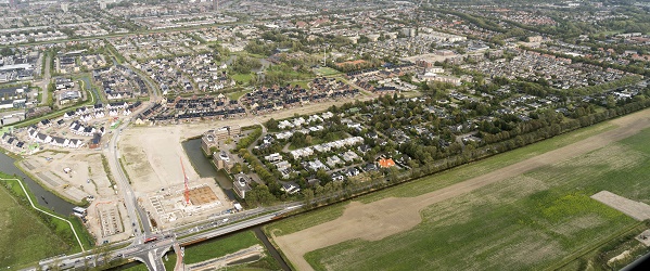 luchtfoto van een diorp met in het midden een bousplaats en nieuwbouwwoningen.