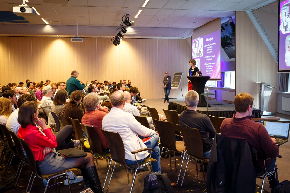 Conference participants discuss a scientific poster at NNV Plasma Physics Symposium Zonheuvel.