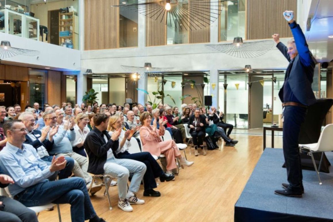 Wim van der Zande raises his arms in triumph in front of the applauding audience at his farewell symposium.