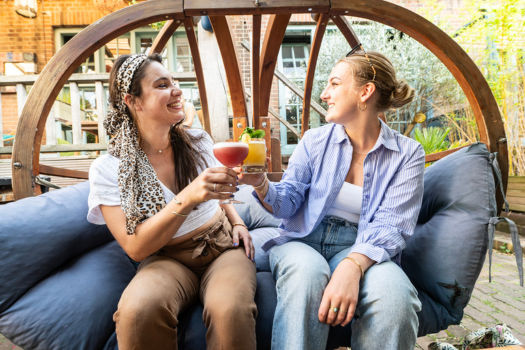 Twee meiden proosten op een zonnig terras