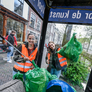 Twee vrouwen met afvalgrijpers en vuilniszakken in hun handen