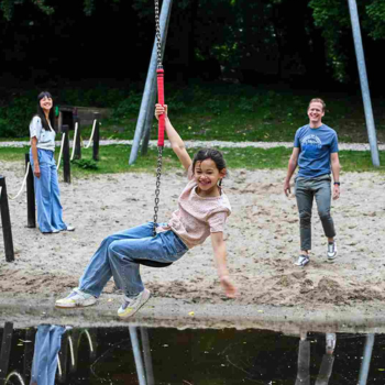 Blij kind op een zipline over het water met vader op de achtergrond