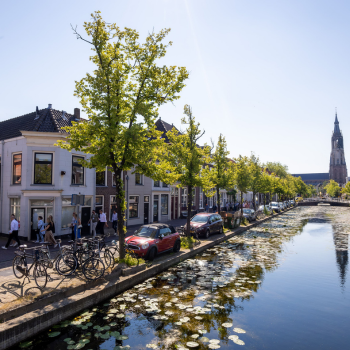 Groep mensen aan het lopen door Delft met de Nieuwe Kerk toren op de achtergrond